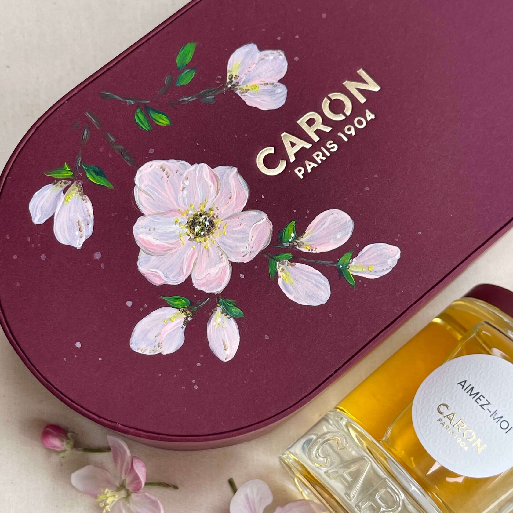 Custom hand-painted Caron Paris luxury perfume box decorated with delicate white and pink floral artwork by Julia Razz.