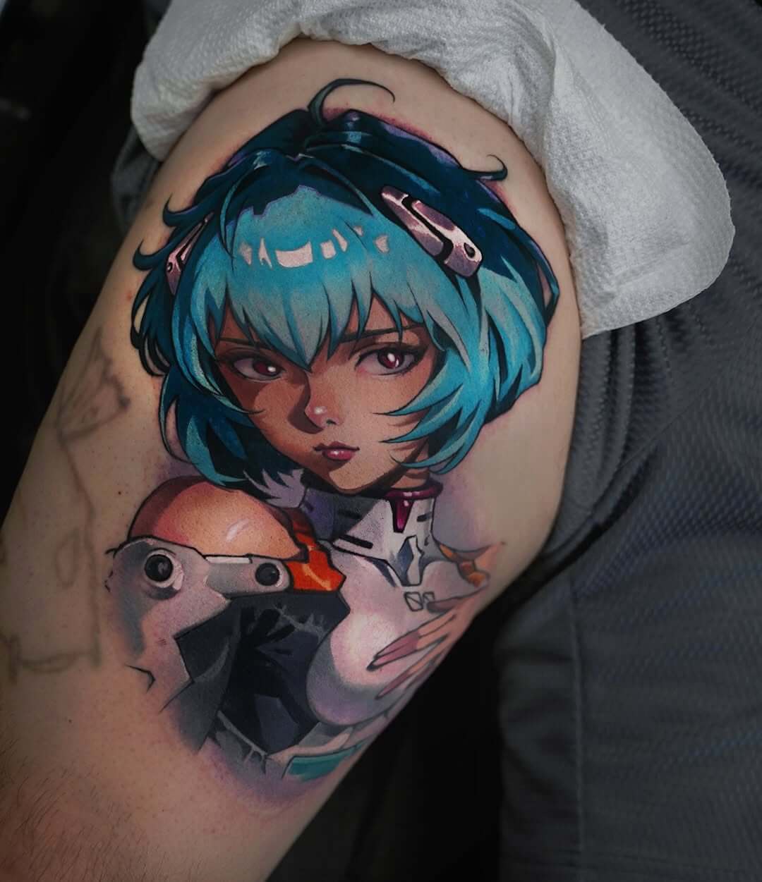 A color tattoo featuring a portrait of Rei Ayanami from the anime Neon Genesis Evangelion. The work is done in an anime-realistic style, with rich blue hair and detailed shoulder armor, a modern geek tattoo.