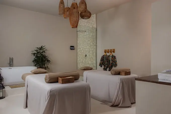 An elegantly designed, minimalist treatment room featuring two massage beds, a bathtub, and woven rattan lamps at Inka Ubud Spa, a boutique option for the best spa in Ubud.