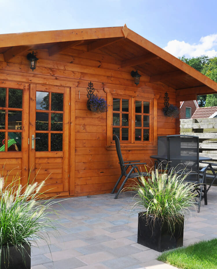 Ein klassisches Gartenhaus in einer Sommerlandschaft, daneben sind Gartenmöbel