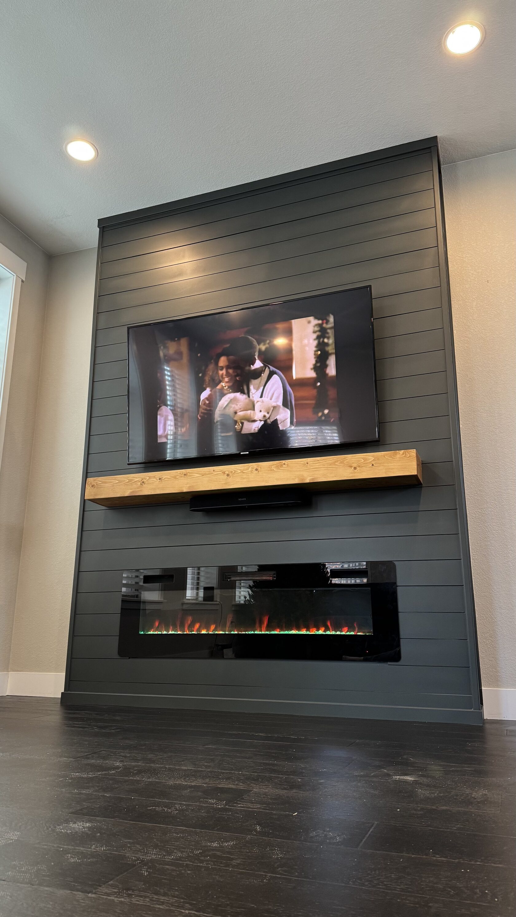 Full-height view of the custom shiplap wall with TV, wood mantel, and fireplace.