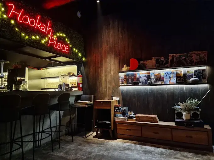 The rustic and laid-back bar area at Hookah Place in Canggu, showcasing a glowing red neon sign, wooden shelves, and a classic no-frills shisha atmosphere.