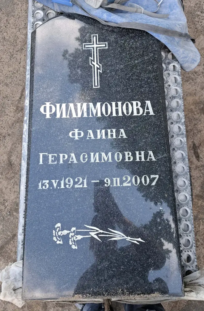 Тёмная фигурная стела до обновления: одна надпись, крест и гравировка цветка внизу.