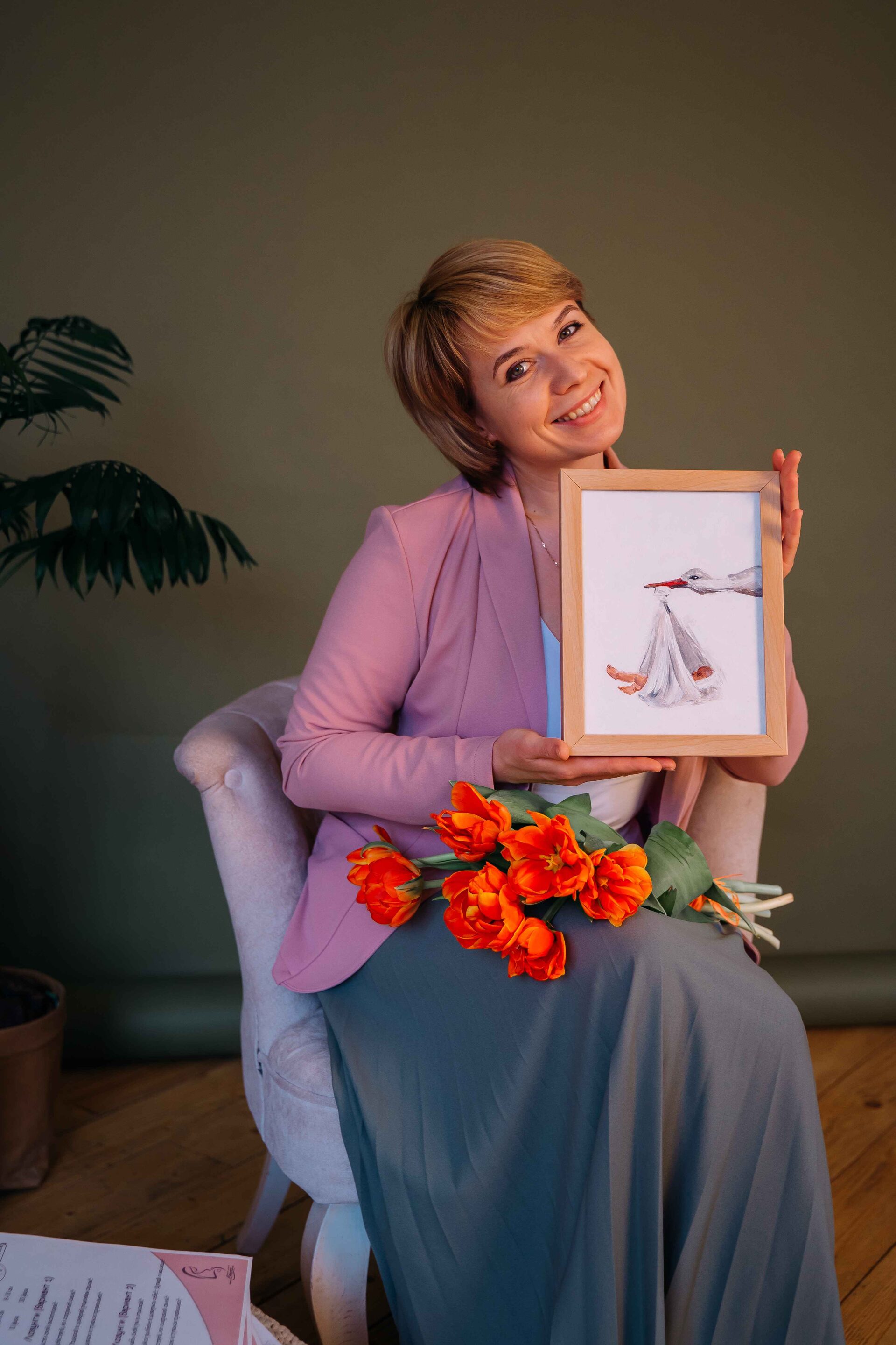 Екатерина держит в руках картинку аиста, приносящего ребёнка