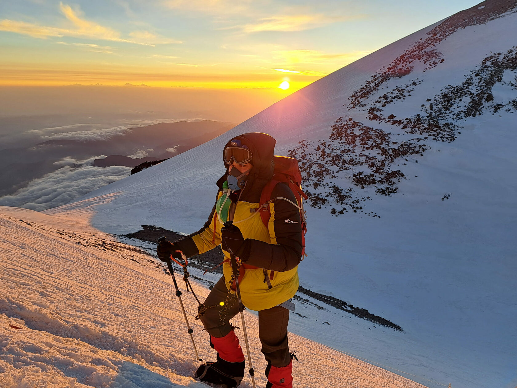 Climber in an oxygen mask on the Elbrus slope at sunrise