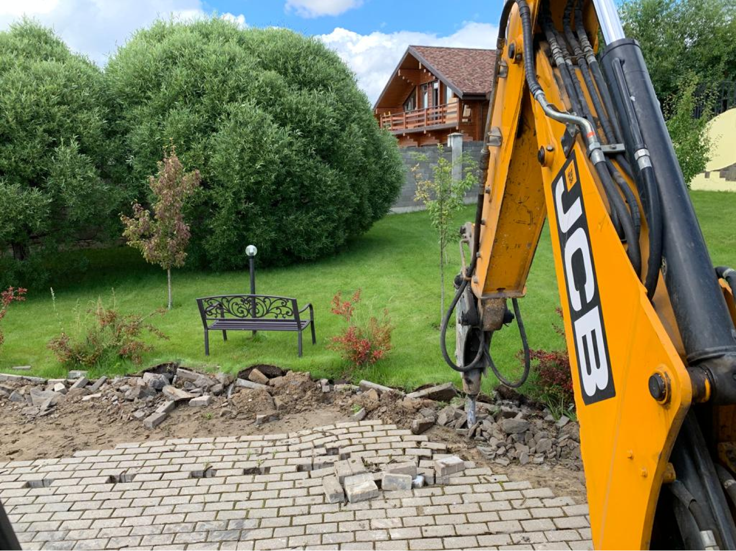 экскаватор погрузчик jcb3cx работает на территории частного дома