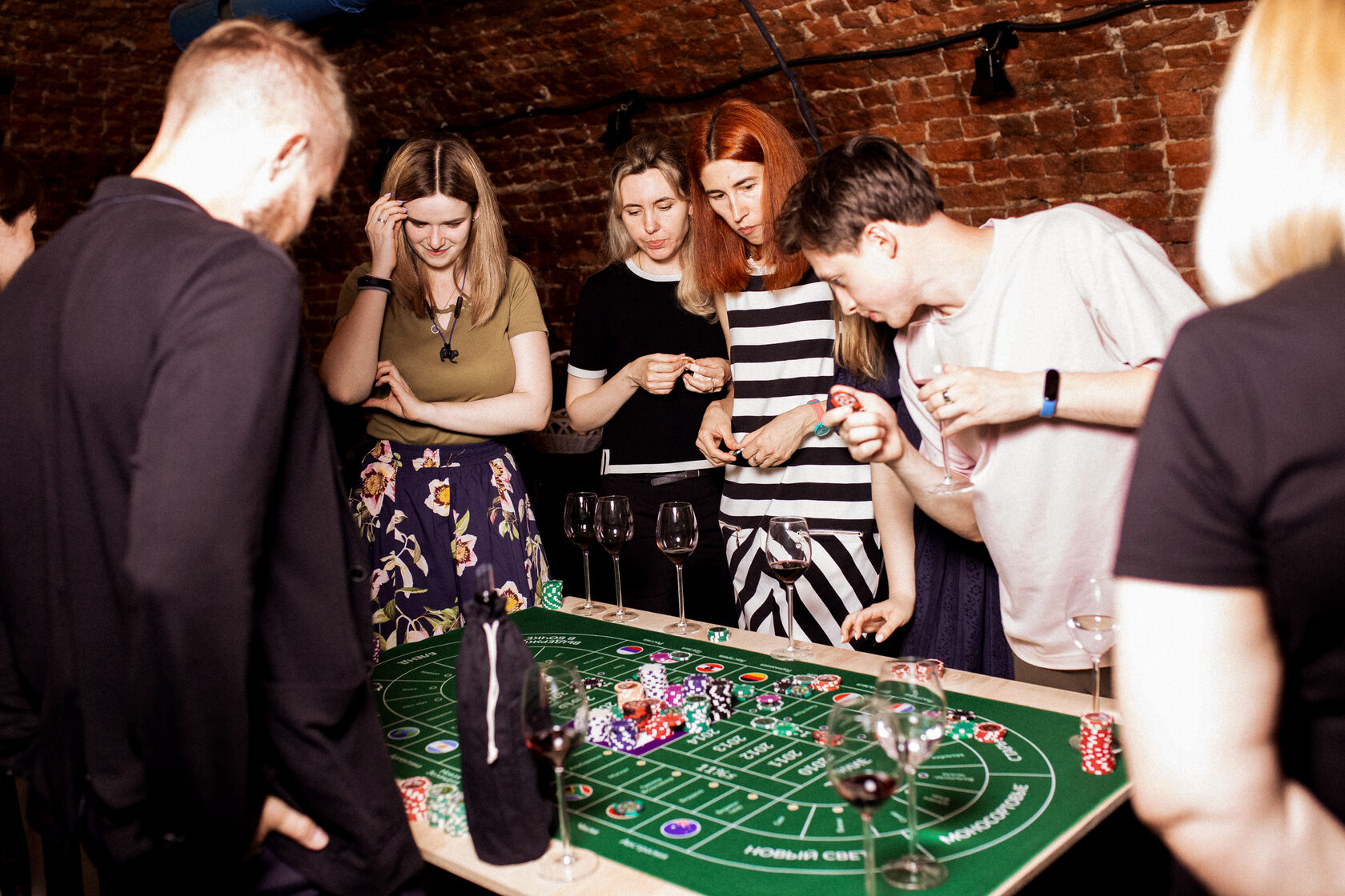 Люди с бокалами вина играют в казино