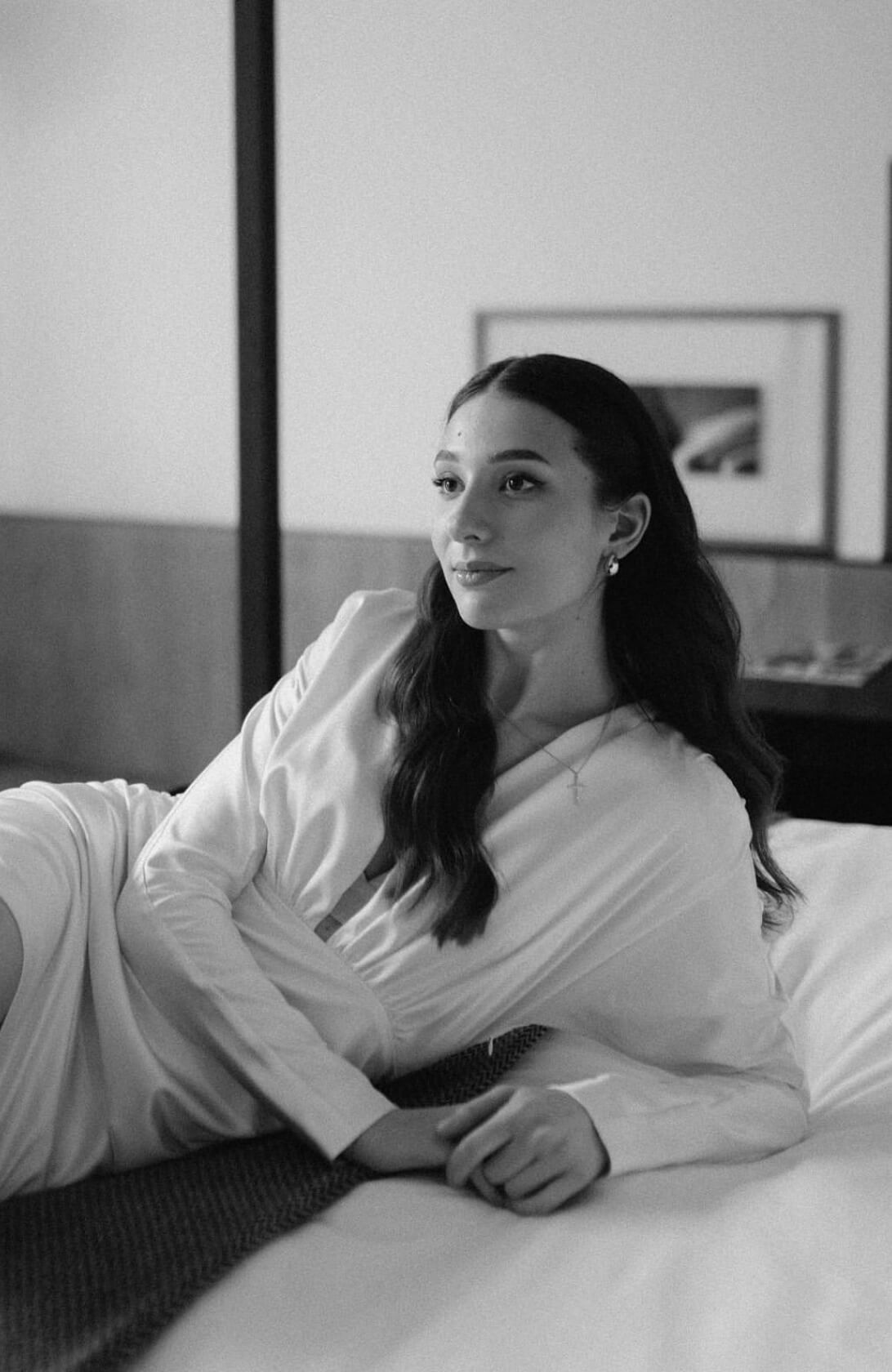 Невеста с локонами лежит на кровати в чб