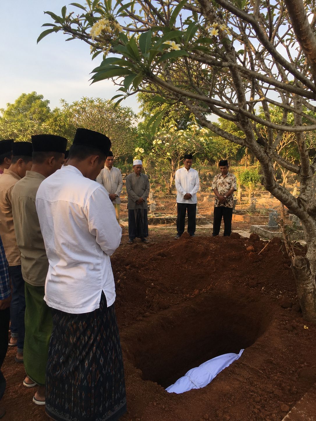 Suasana pemakaman Muslim di desa Indonesia dengan proses penguburan yang berlangsung khidmat