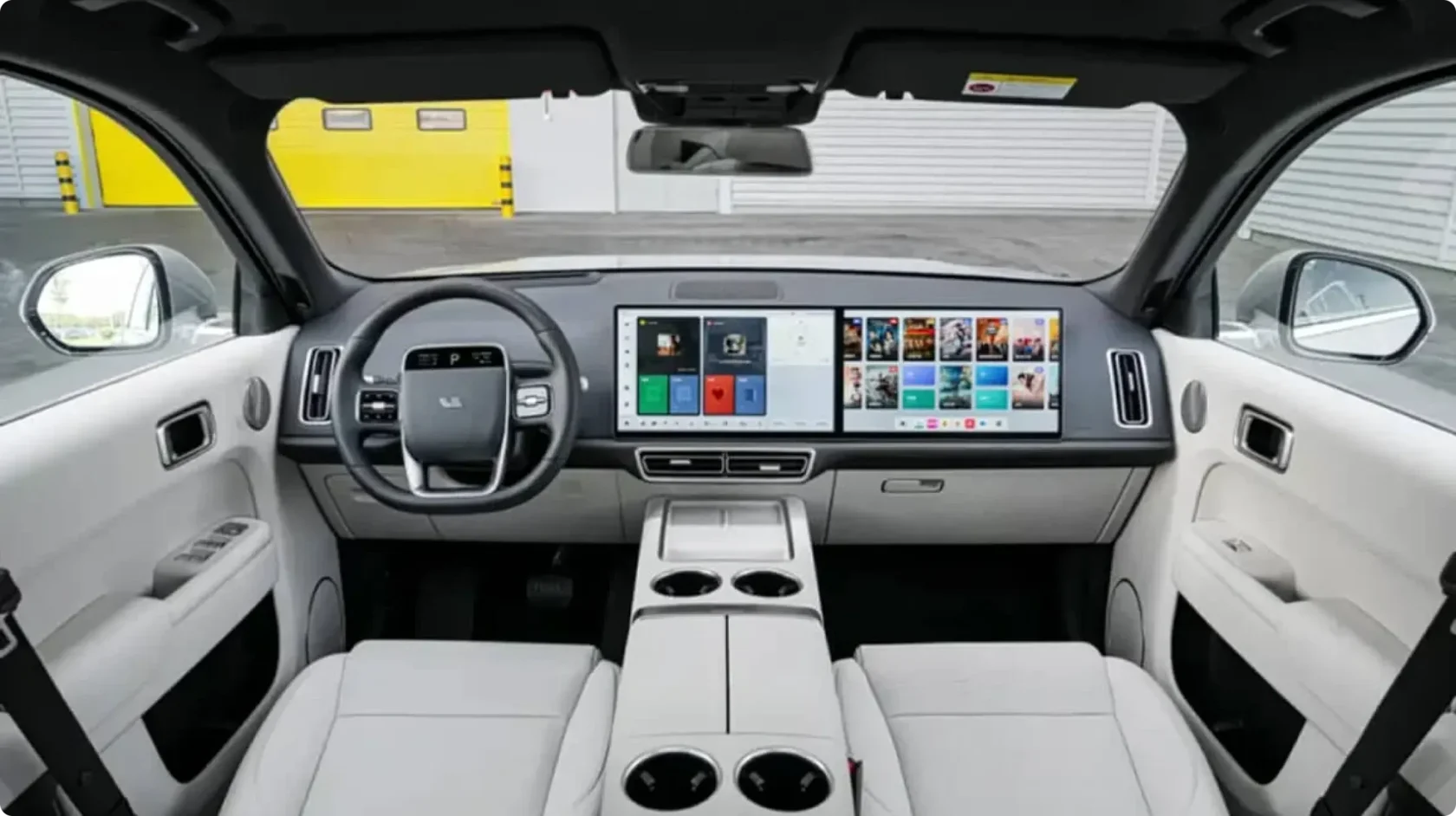 Светлый просторный салон Li Auto L9 Livis с двумя широкоформатными экранами мультимедиа, руль с логотипом и центральная консоль с подстаканниками, интерфейс системы автопилота на основе процессоров Mach 100