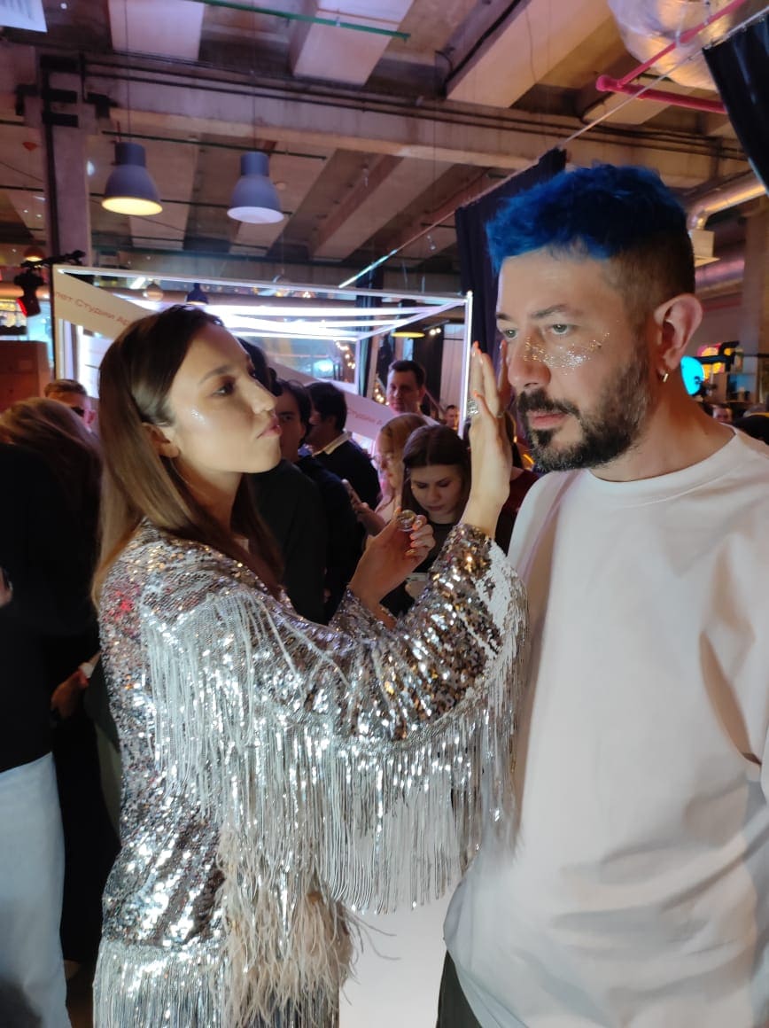 Визажист наносит брендированные блёстки гостю мероприятия