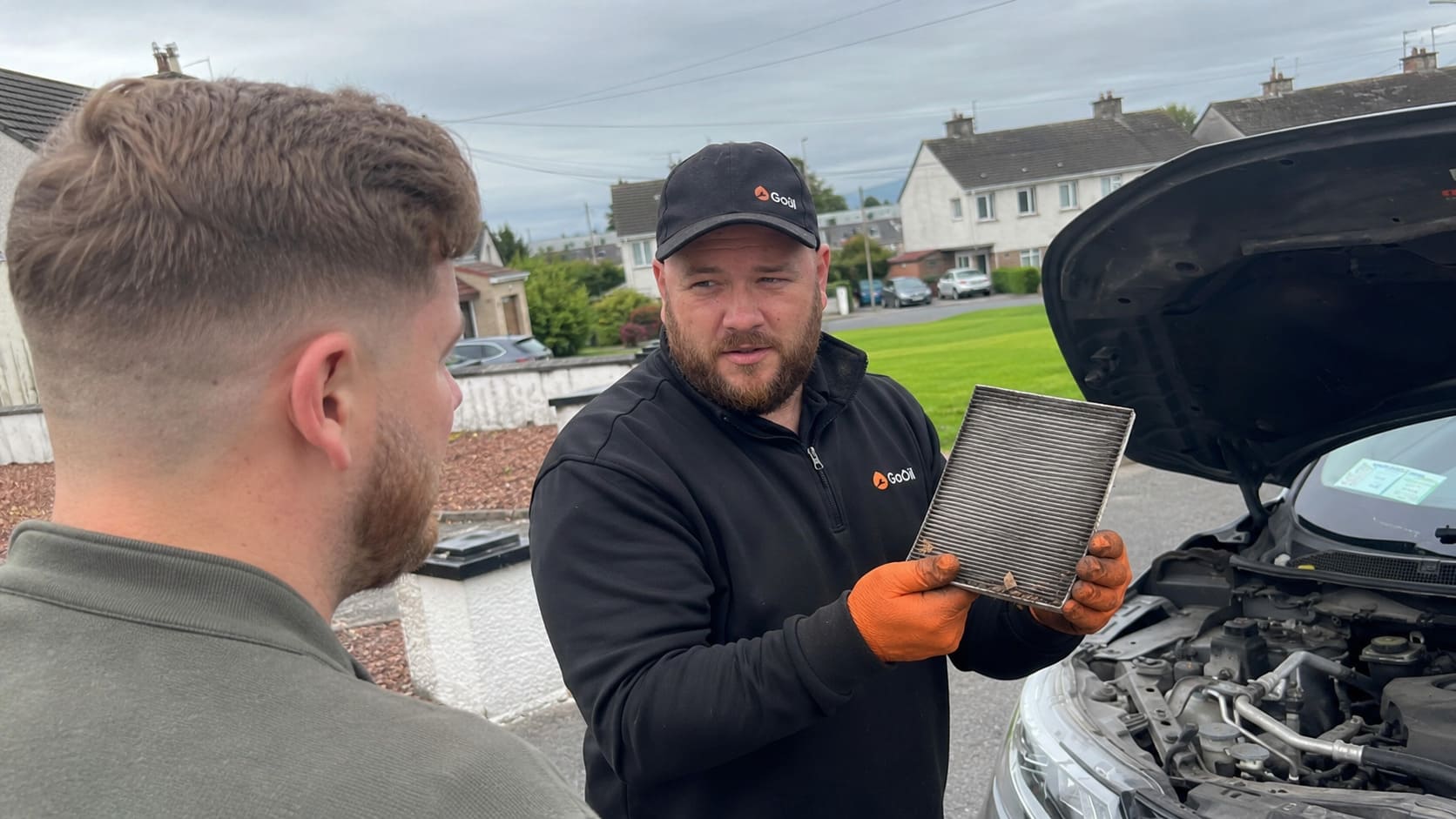 Mechanic showing a dirty cabin filter to a customer during a mobile car service