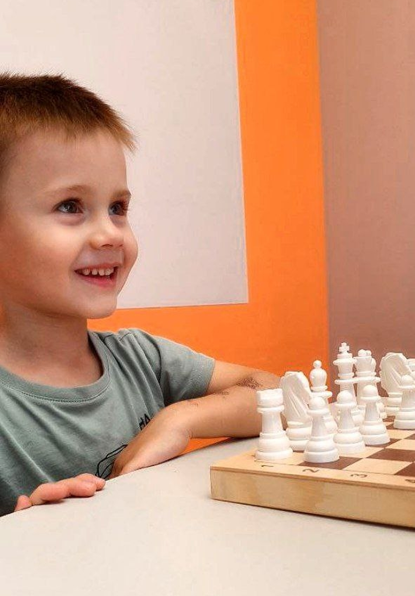 Мальчик играет в шахматы за столом