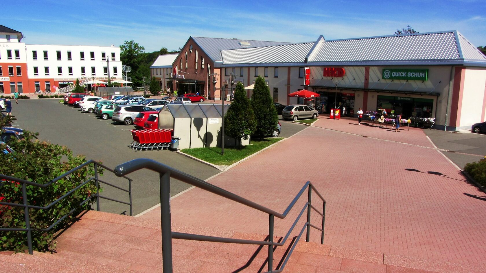 Modern retail buildings with a car park and steps