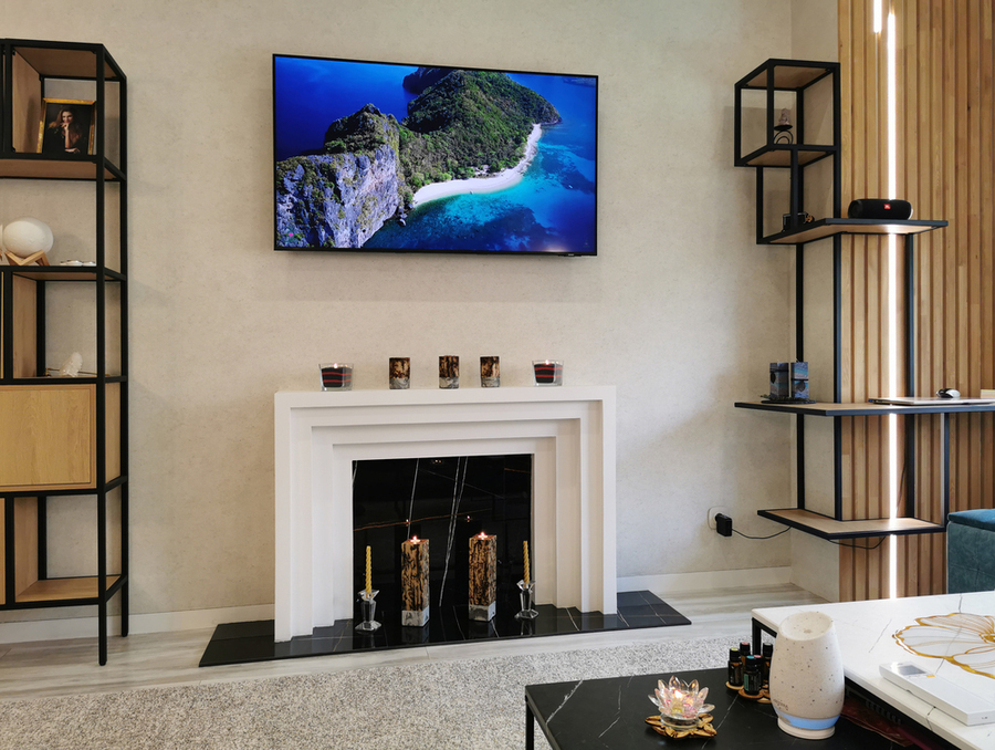дизайн гостиной в тёплых оттенках, белым каминным порталом под телевизором, деревянными рейками с подсветкой