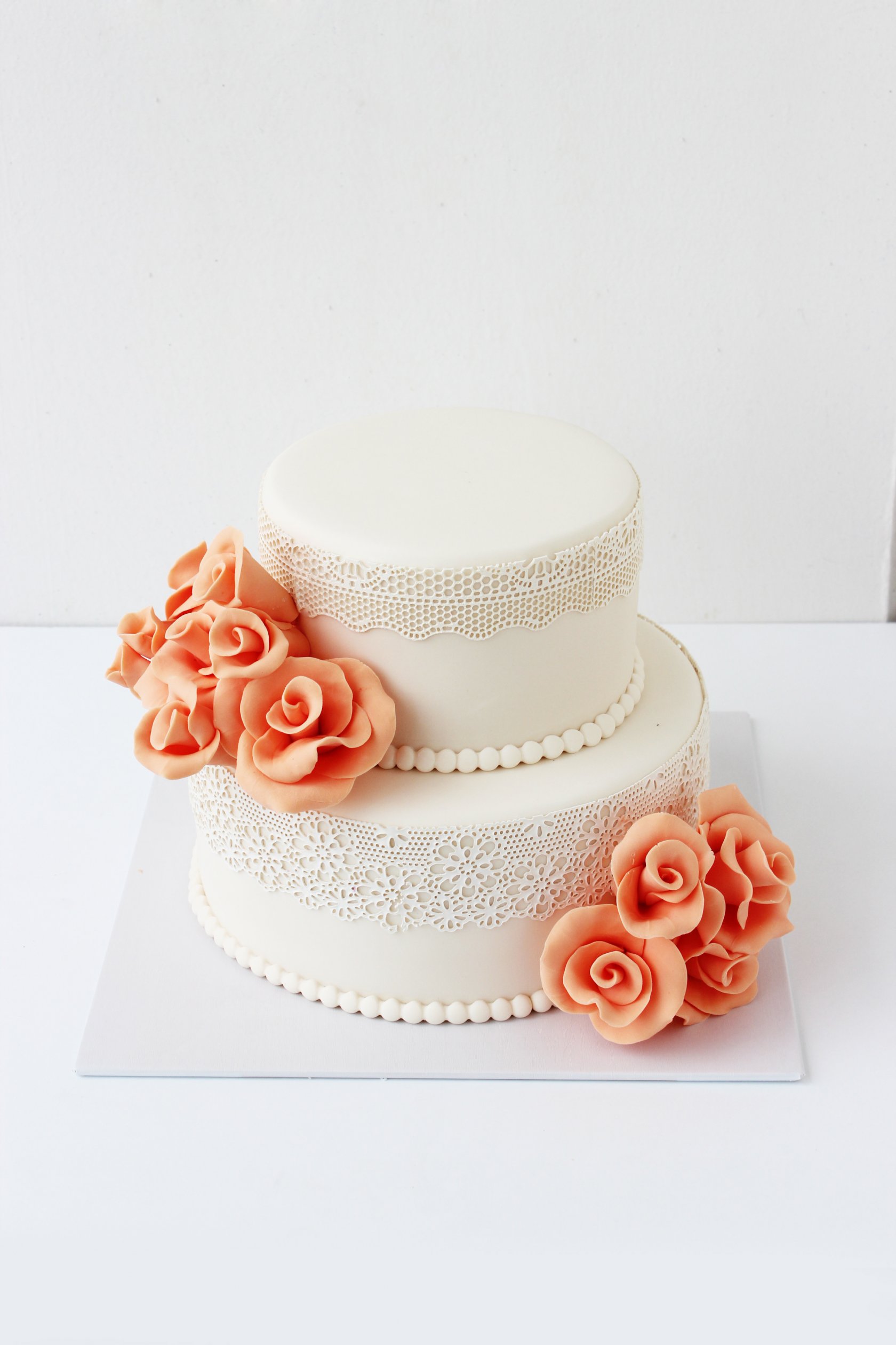 Свадебный торт в два яруса розового цвета украшенный цветами из мастики в темно ярком розовом цвете