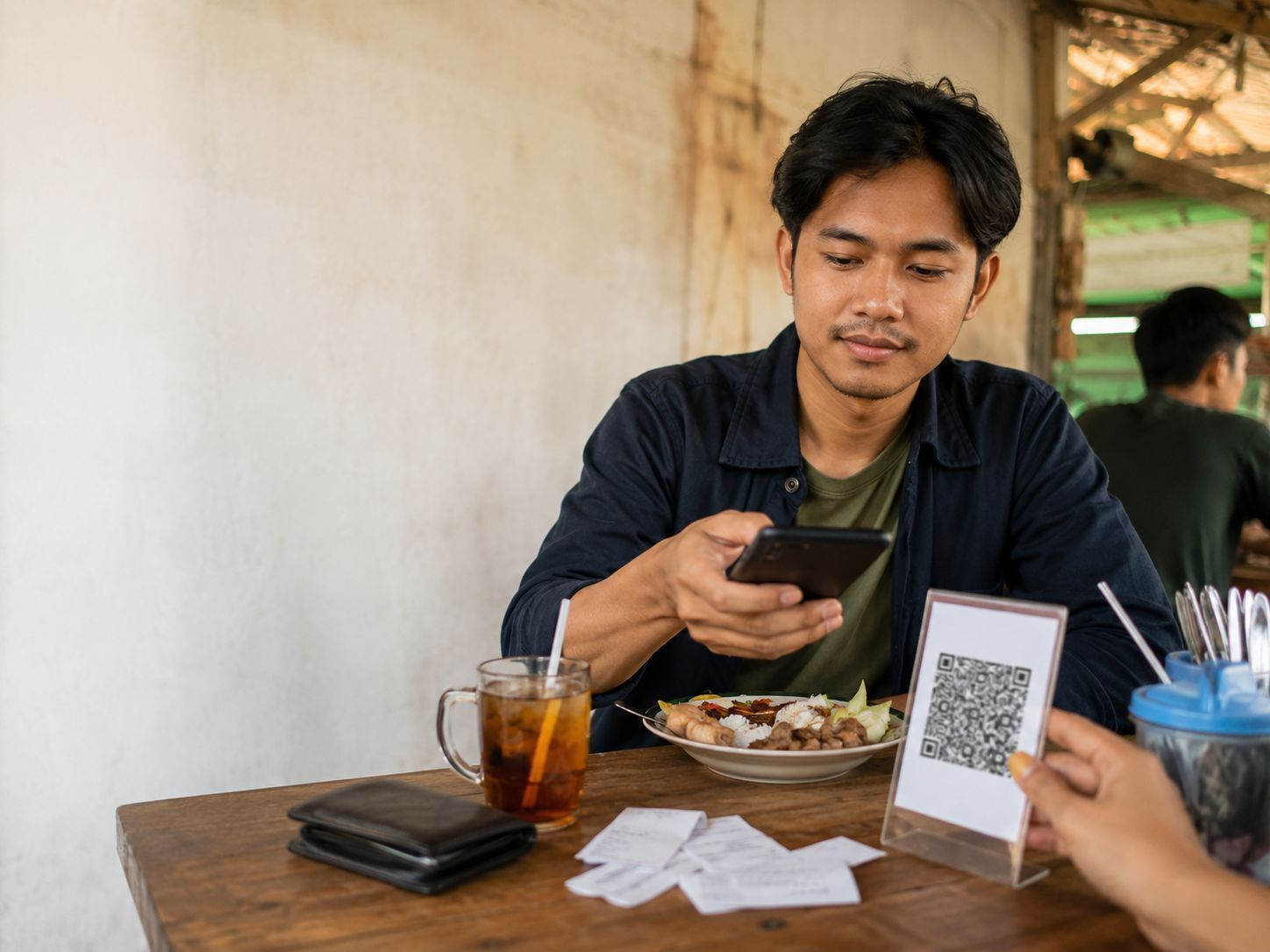 Pekerja muda membayar makan siang dengan QRIS sambil memperhatikan pengeluaran harian