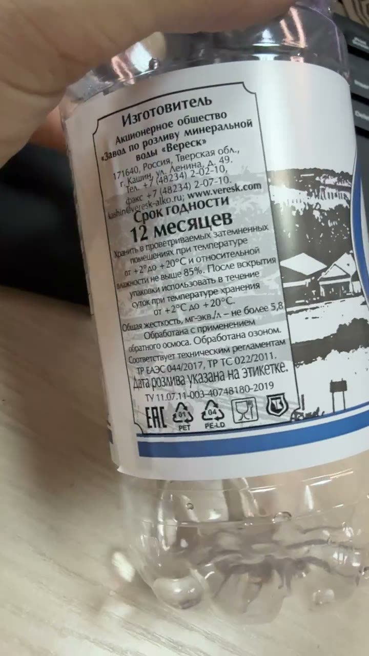 Оборот бутылки воды «Кашинская» издалека: под текстом светло-серый пейзаж