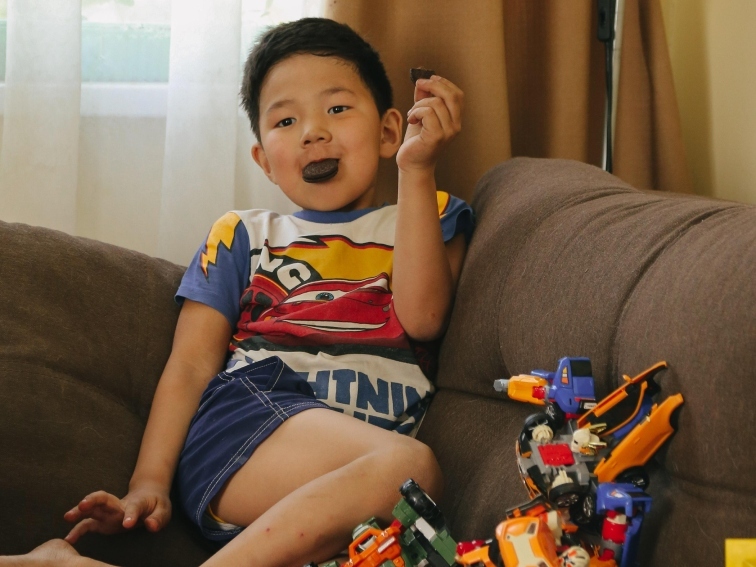 Аюр сидит на диване с игрушками