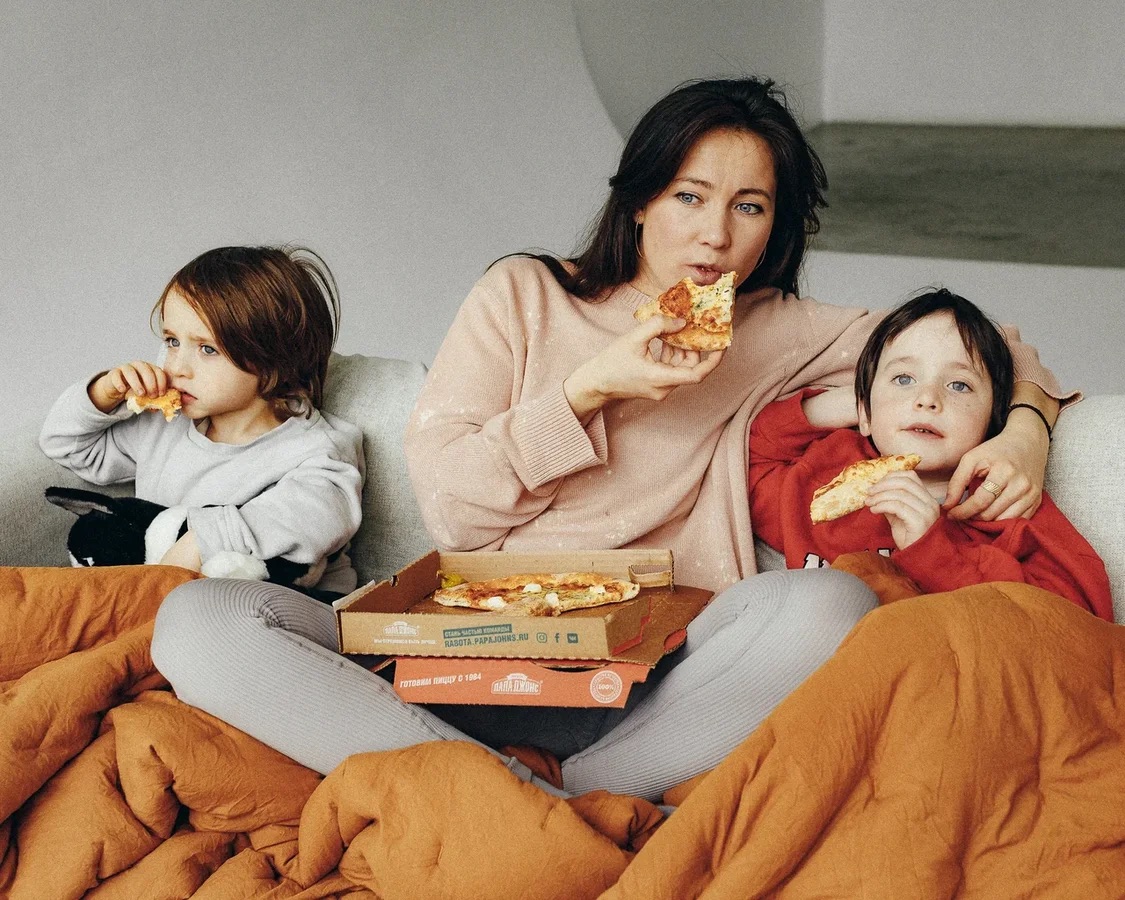 семья ест пиццу за просмотром мультика