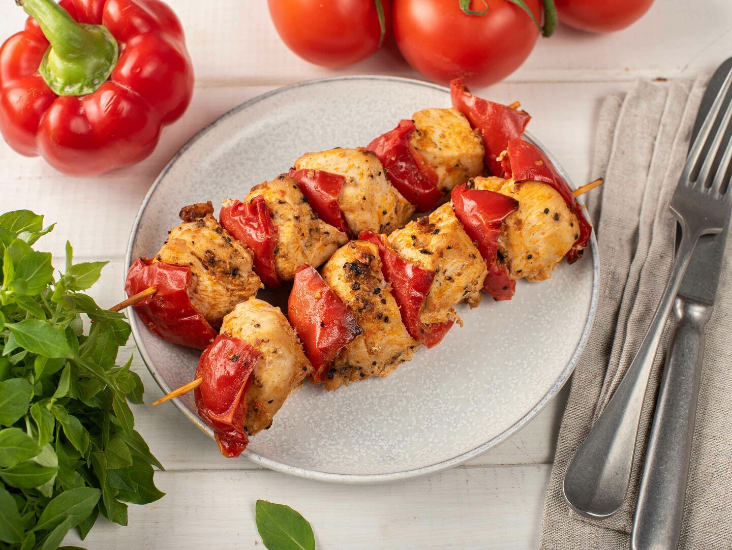 Детский шашлычок из куриного филе на тарелке с перцем и зеленью