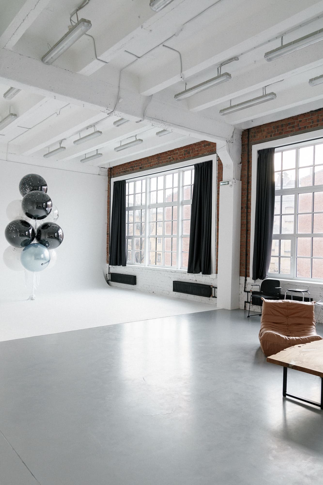 Панорама современной лофт-фотостудии с высокими потолками, кирпичными стенами и большими окнами