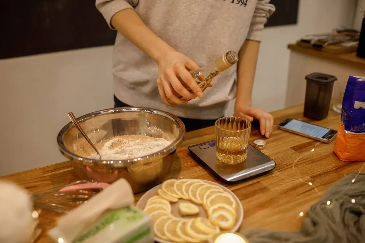 Руки участницы, замешивающей тесто: миска, весы, дольки лимона