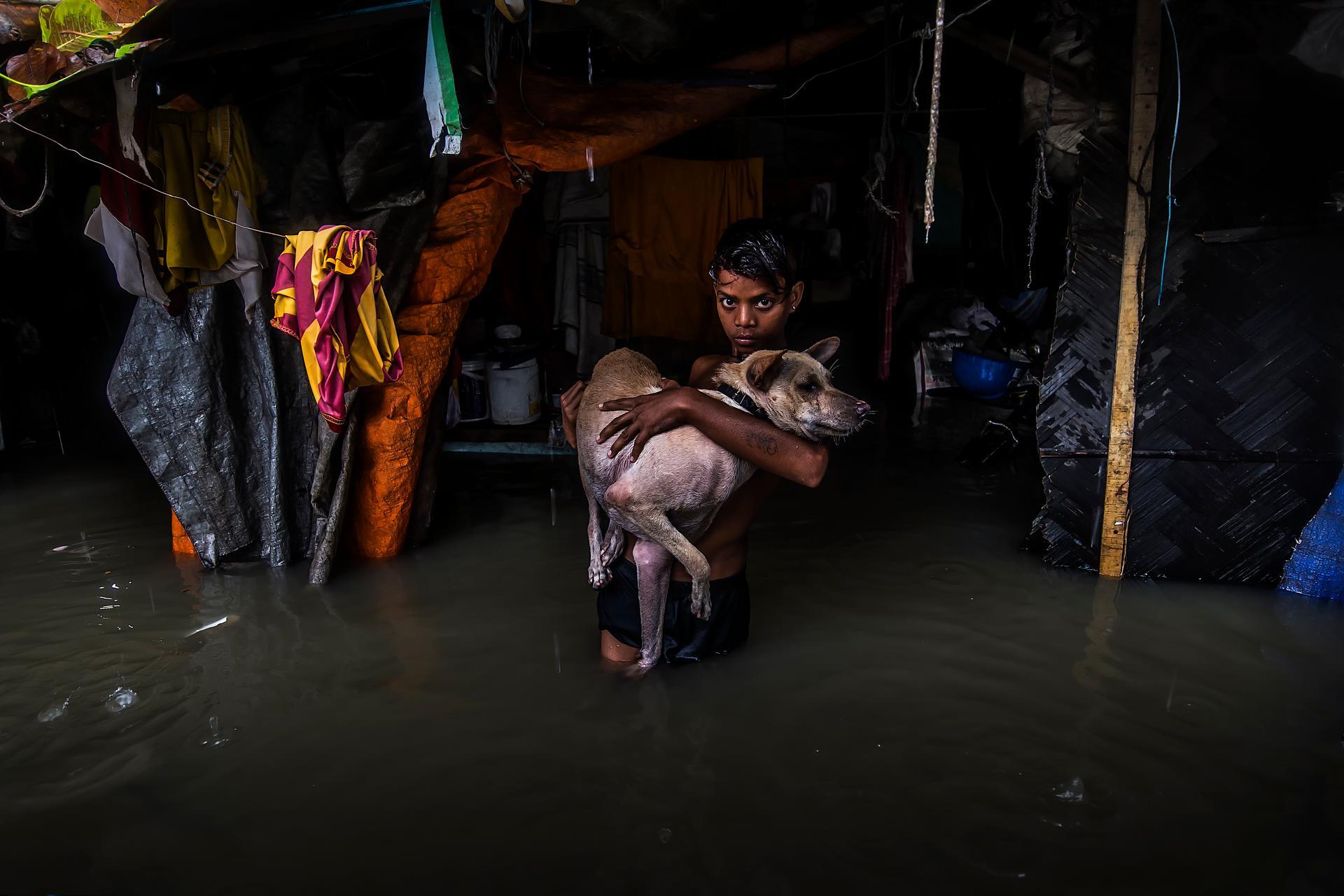 India | Joydip Mukherjee. A young boy attempts to save his pet as rising floodwaters enter his neighbourhood