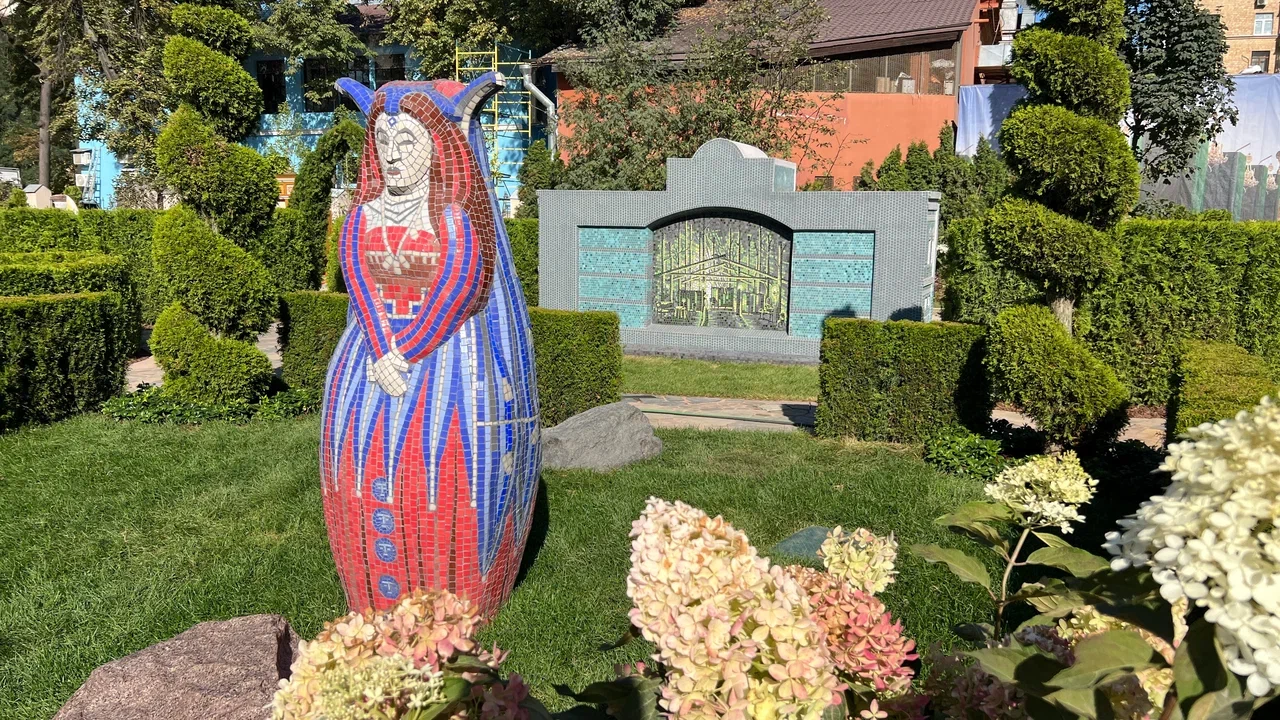 Скульптура-матрёшка в образе царицы, покрытая мозаикой, стоит на газоне музейного двора