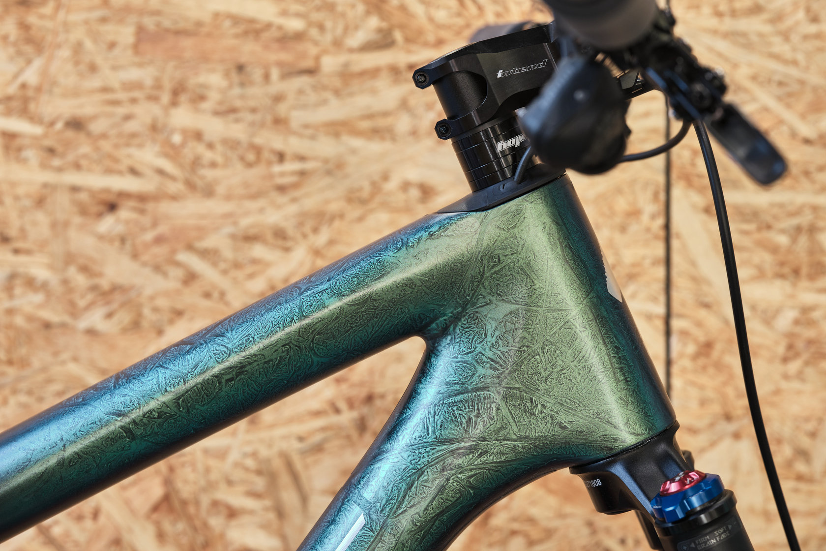 Рулевой стакан зелёной рамы велосипеда Specialized в защитной плёнке на фоне стены мастерской