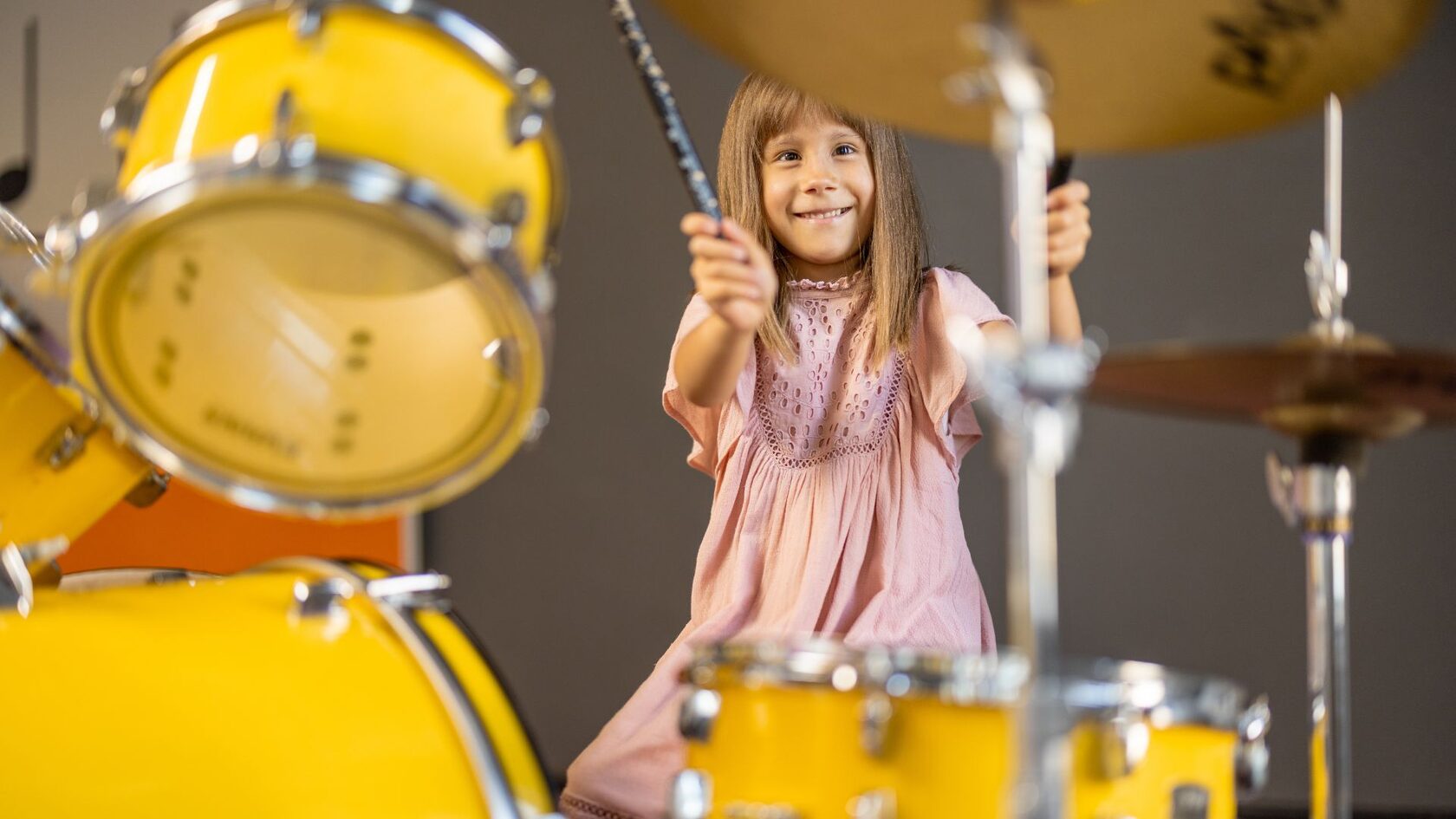 Девочка играет на барабанах на уроке музыки