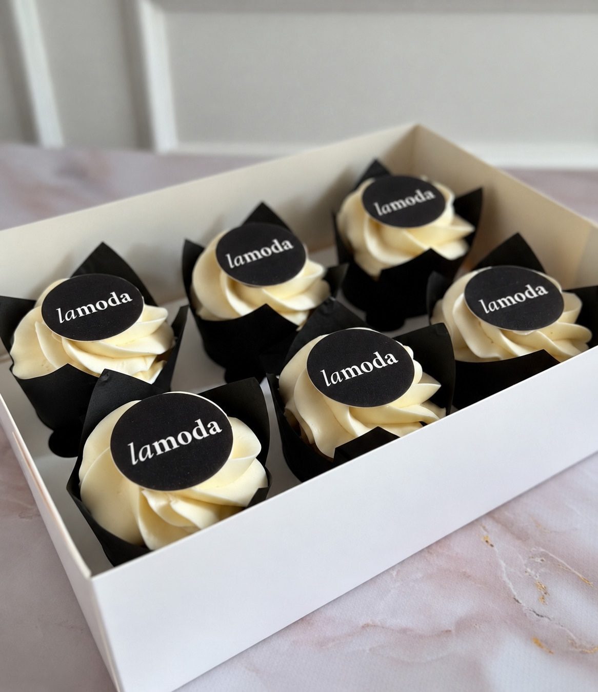 Коробка с шестью капкейками, на каждом — логотип Lamoda