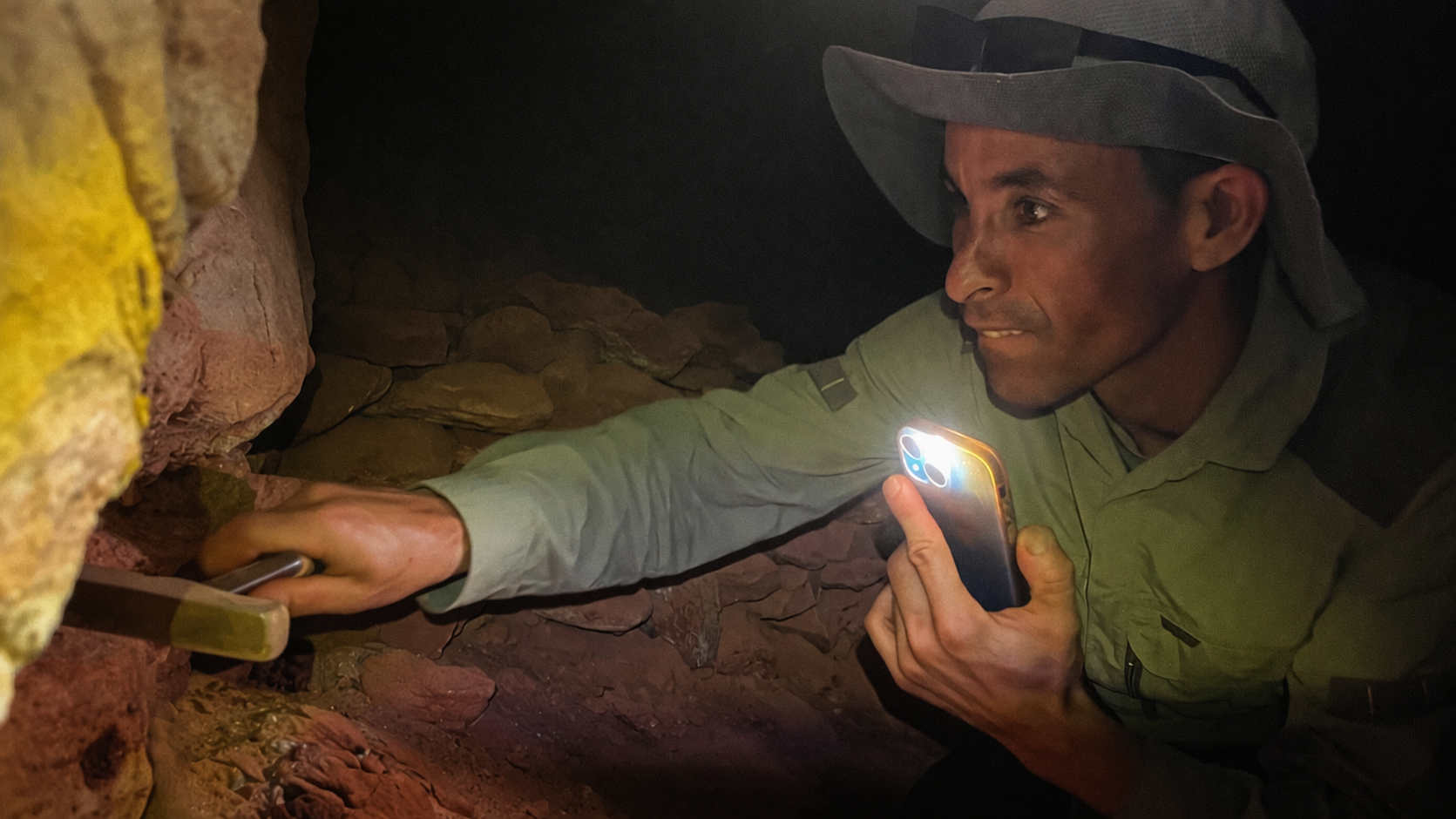 close up of fossil hunter working with tools and light in rocky formation in Sahara