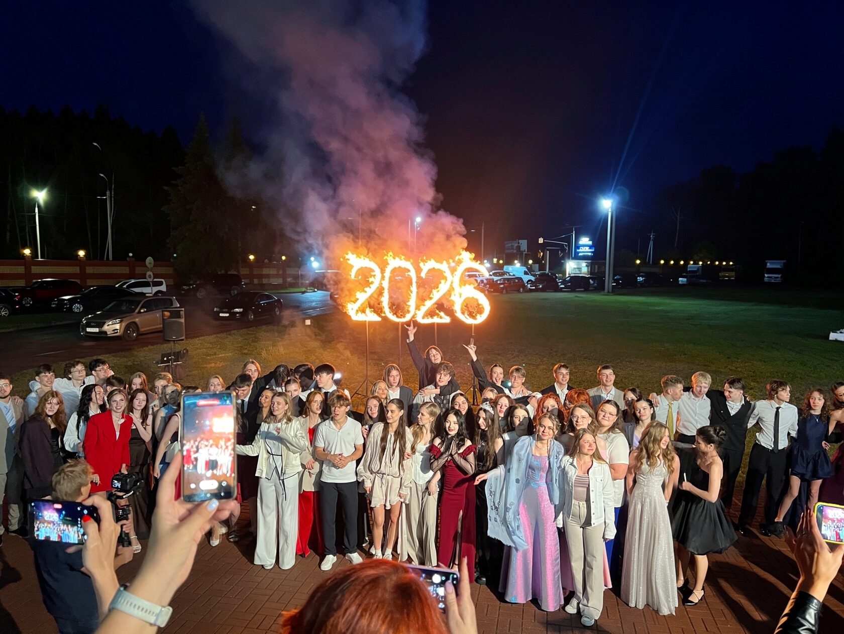 Группа выпускников на фоне огненных 2026