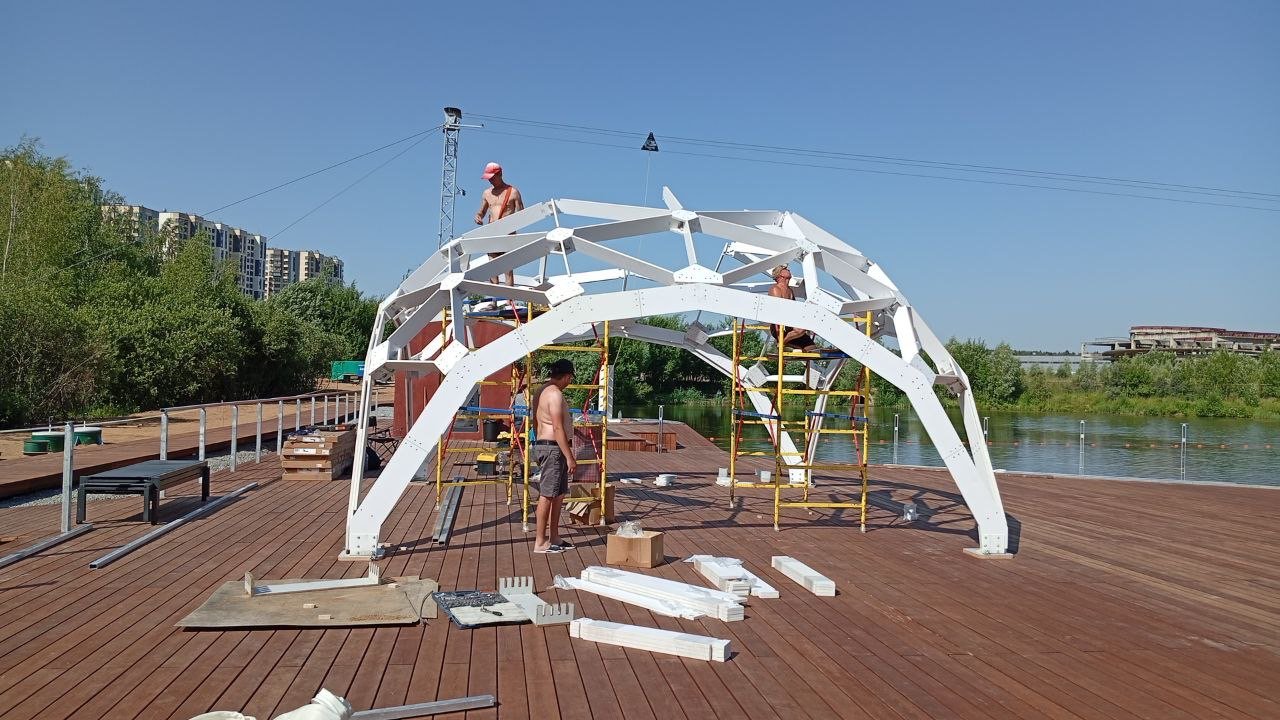 Сборка белого каркаса купола на причале у воды