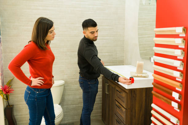 Attractive couple measuring furniture Handsome man and beautiful woman using a tape measure on a bathroom cabinet to remodel their house at the shop bathroom remodeling costly  stock pictures, royalty-free photos & images