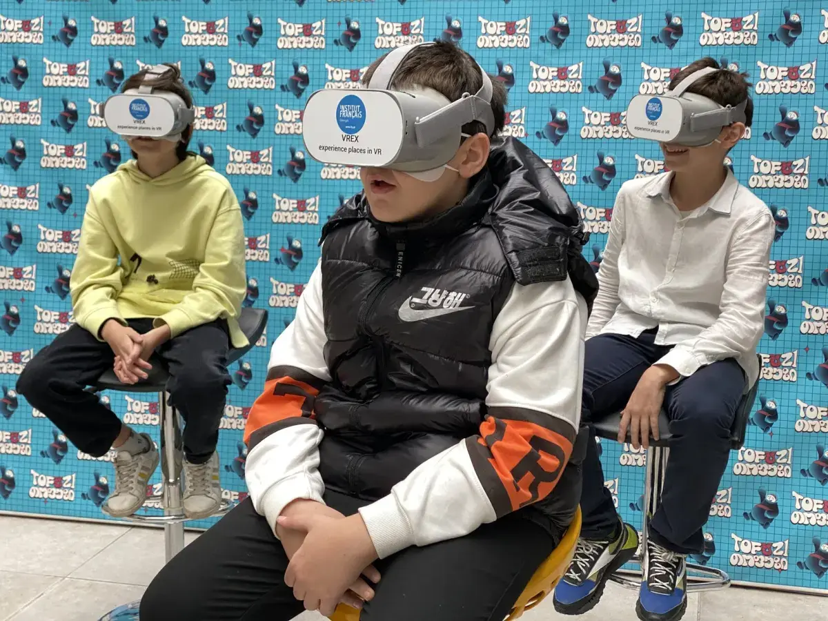 Three young visitors watching VR together in front of a TOFUZI backdrop