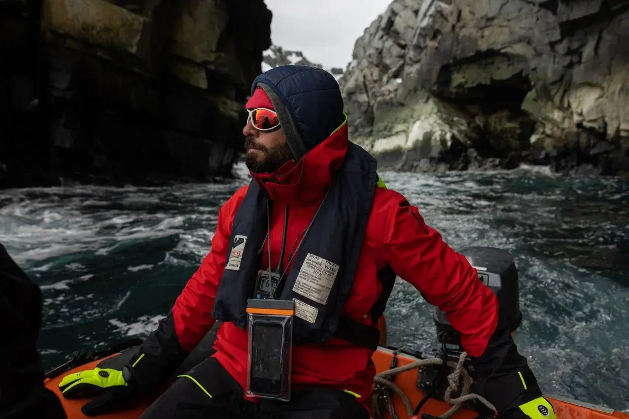 Professional polar guide navigating a Zodiac through remote Arctic waters, equipped for challenging weather and coastal landings. Experienced expedition guides lead small-group adventures, wildlife encounters and shore explorations during sailing expeditions in Greenland and the Arctic.