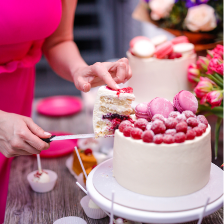a girl in a pink dress cuts a delicious cake on a celebration
