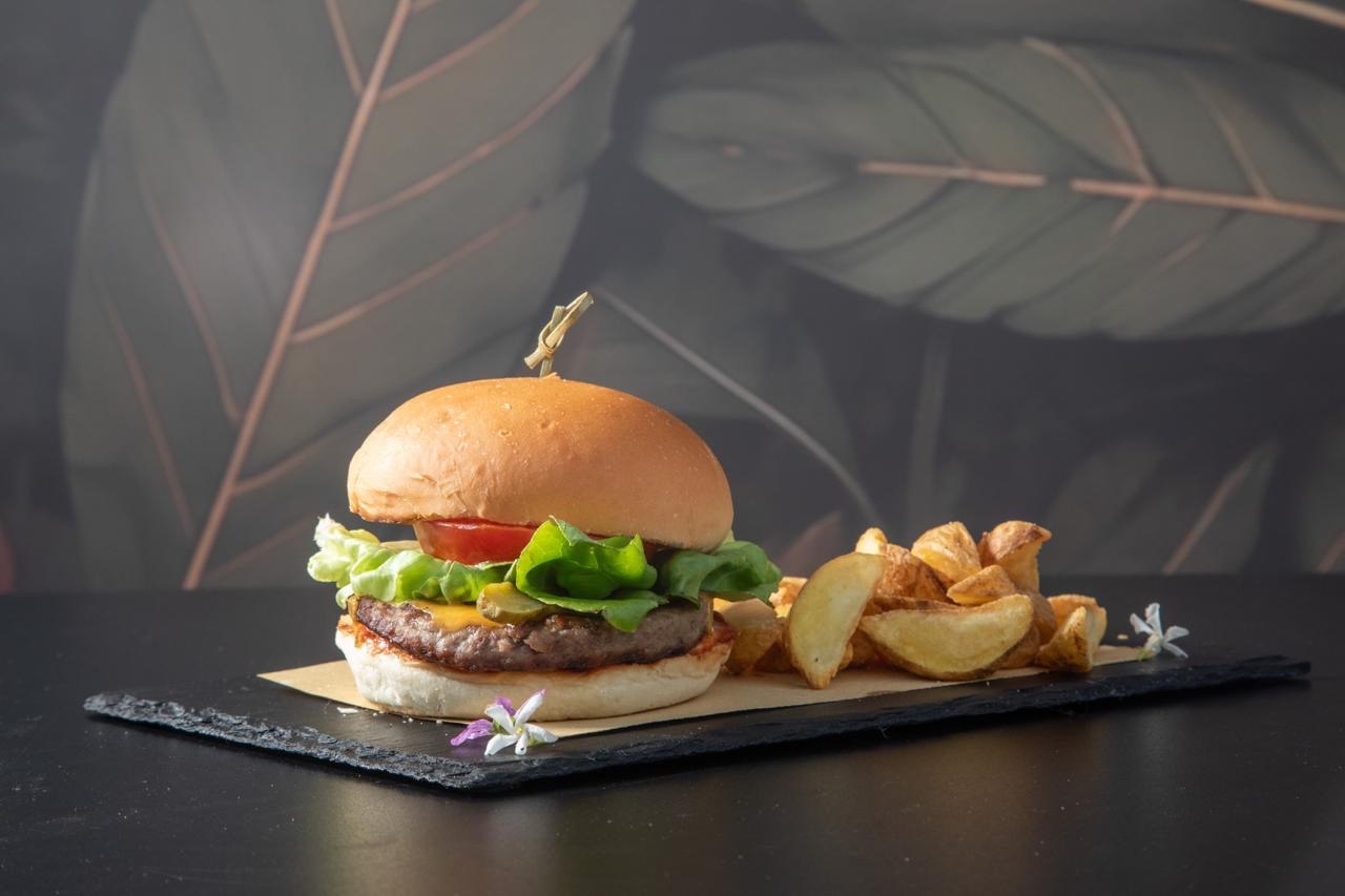A hamburger with beef patty, melted cheese, lettuce and tomato on a plate