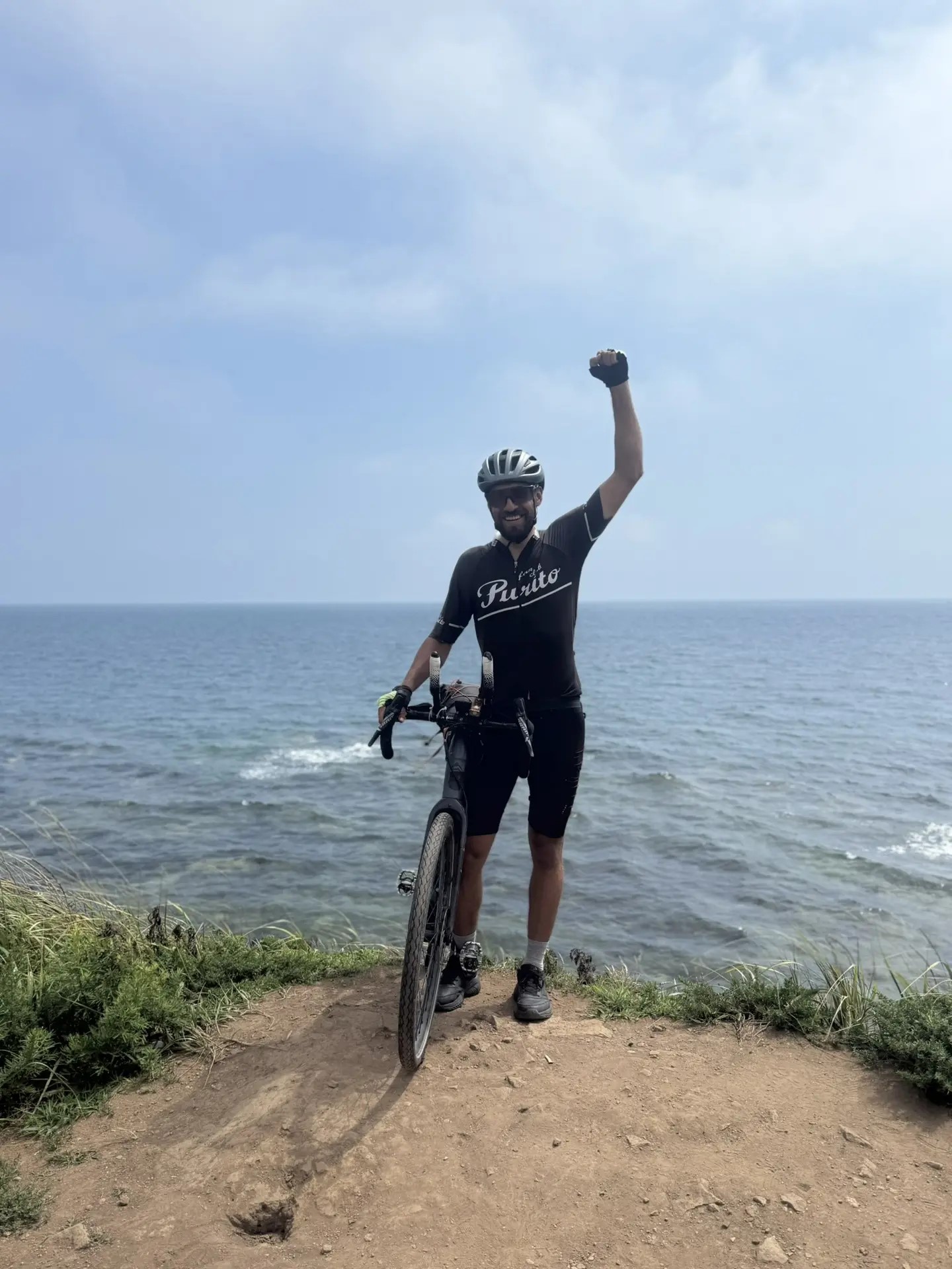 Велосипедист в чёрной футболке Radko побеждает на берегу моря