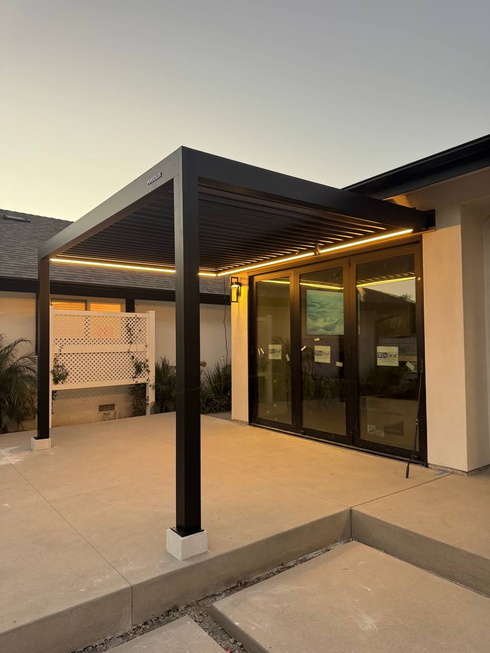 Evening view of the illuminated pergola and reflections in the glass patio doors.