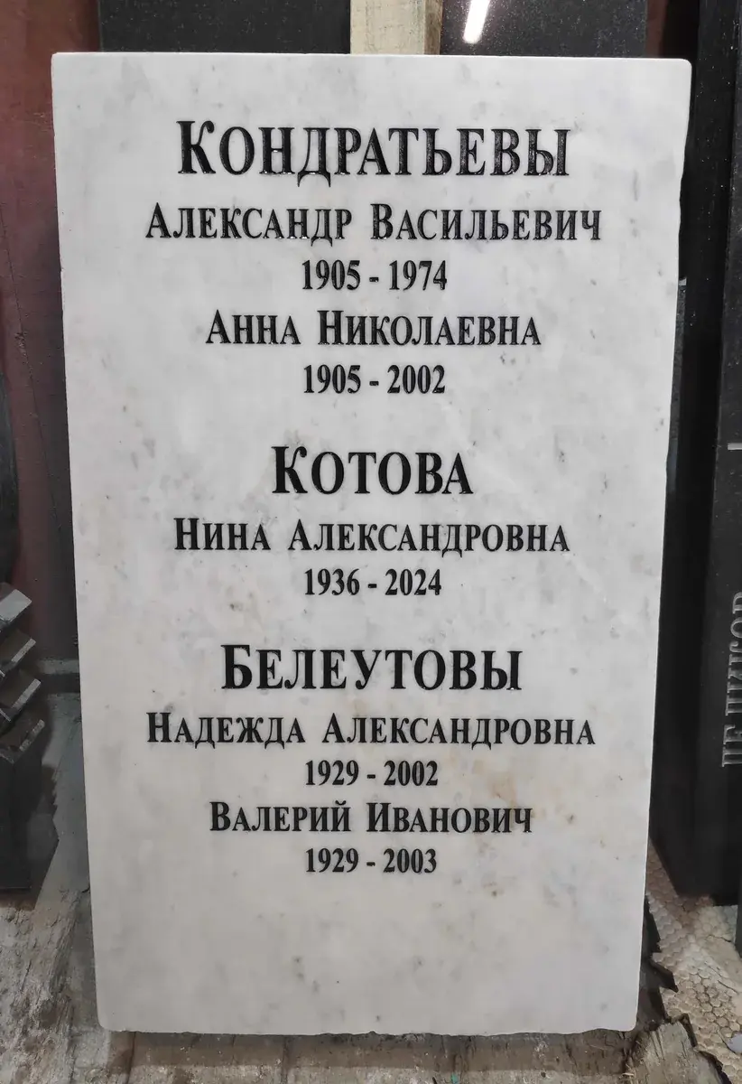 Светлая прямоугольная стела после обновления: новые чёрные надписи для нескольких членов семьи.