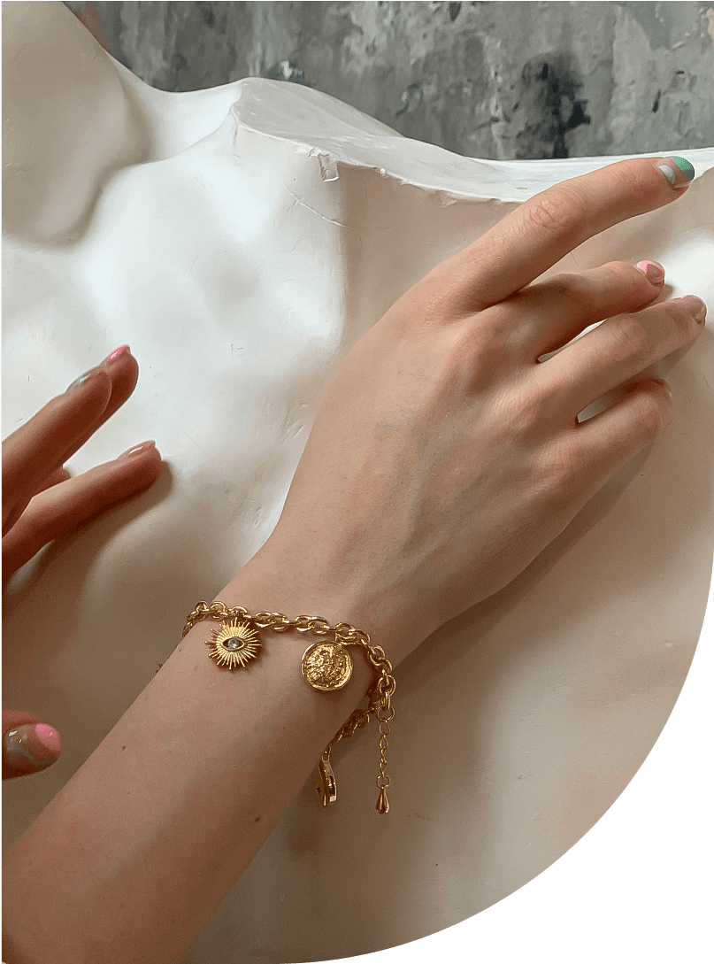 рука девушки в золотом браслете с магическими символами-солнцем луной монетой 