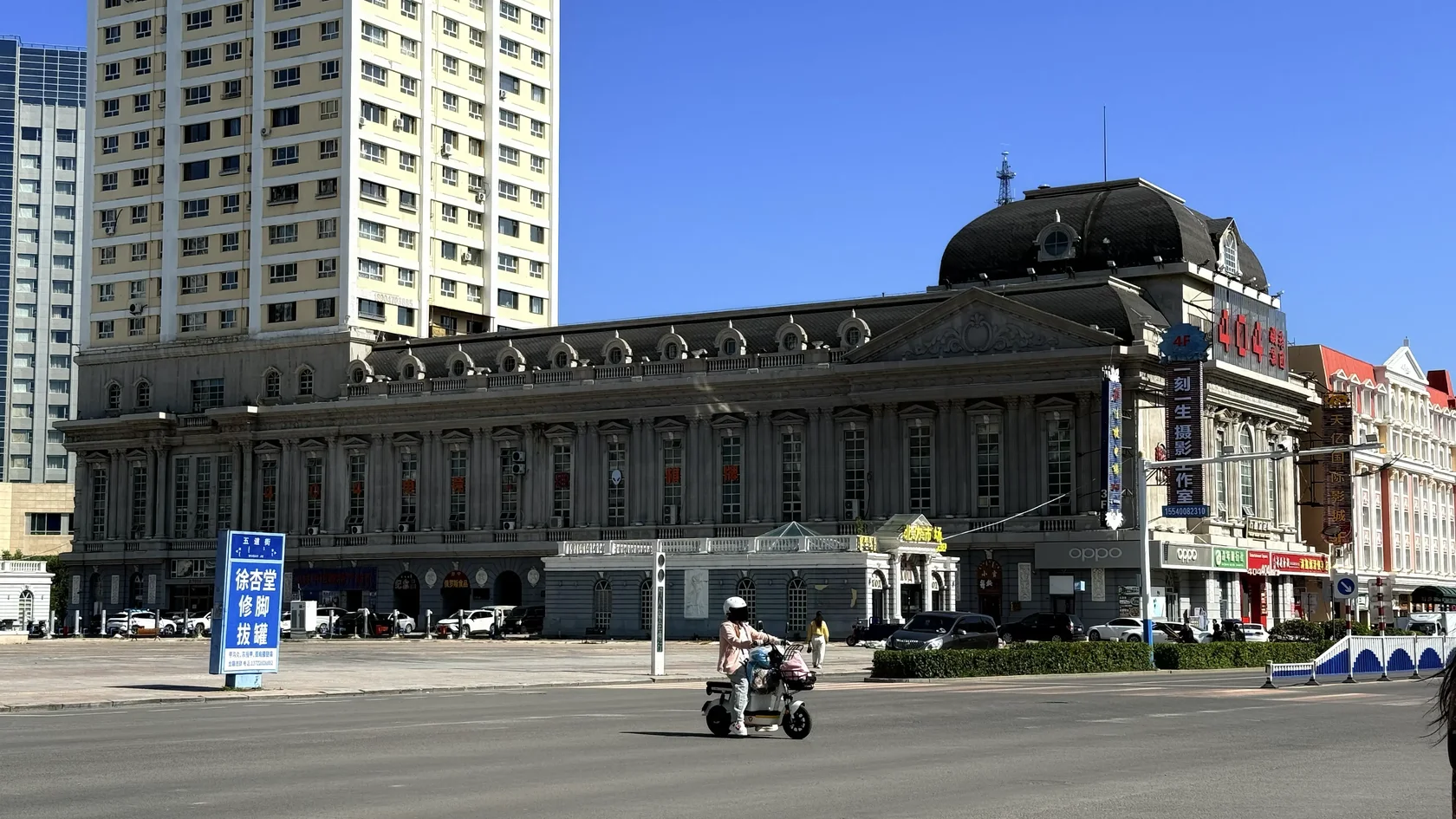 Здание с колоннами и тёмной крышей у городской дороги