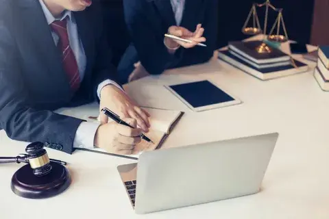 Юрист по банкротству физических лиц консультирует клиента, на столе — документы и ноутбук.