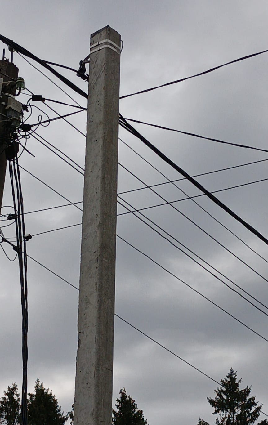 Железобетонная опора ЛЭП с проложенными проводами на фоне неба