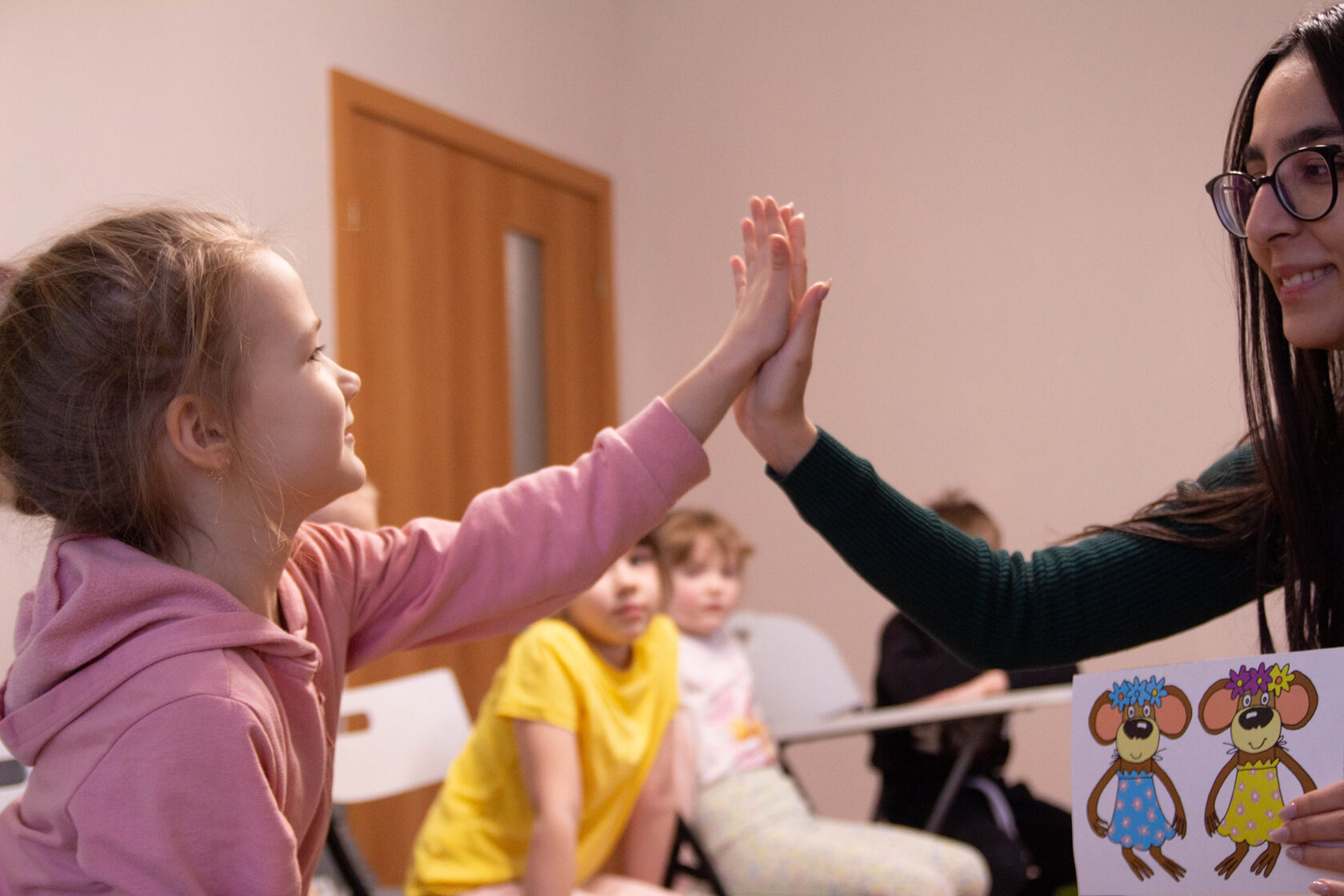 дети на занятии англйским языком радуются вместе с преподавателем