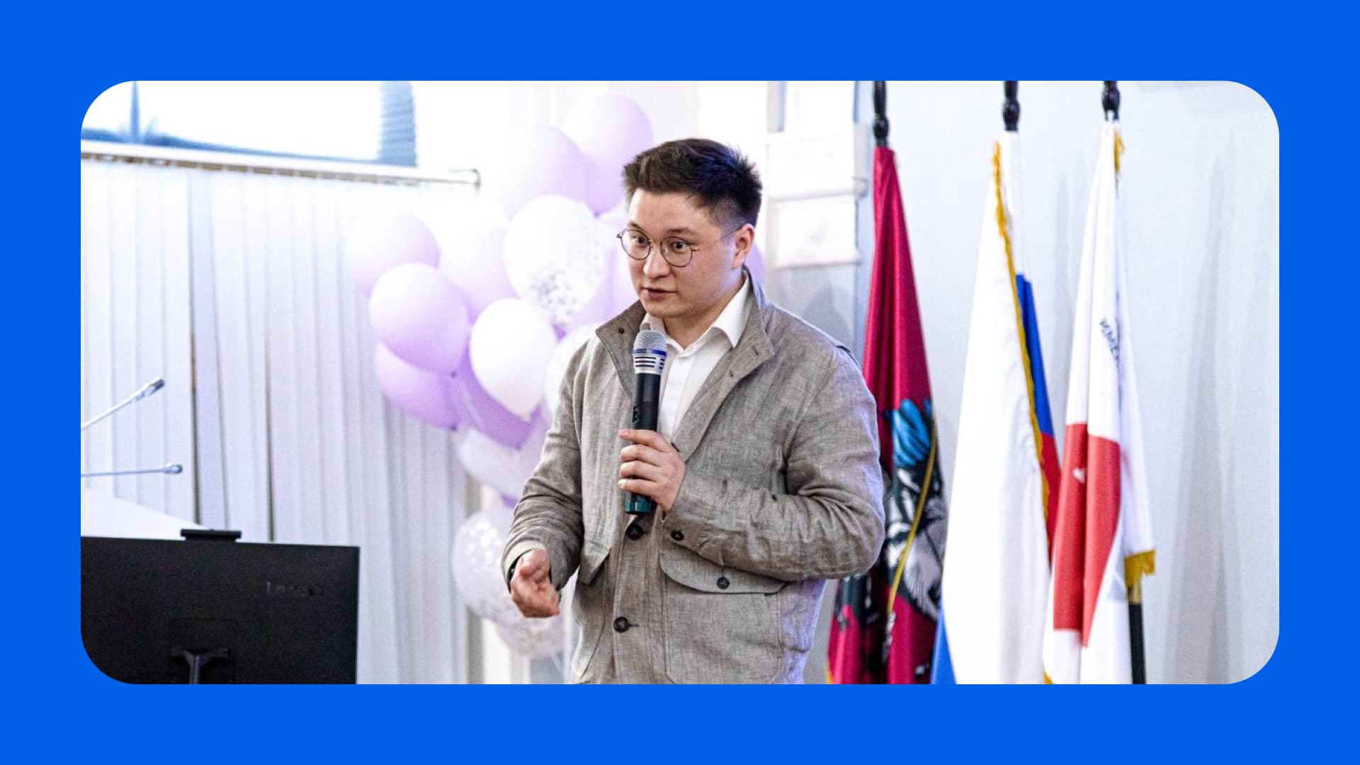 Владислав Радов читает лекцию для школьников в зале с колоннами и флагами, подготовка к олимпиаде по праву