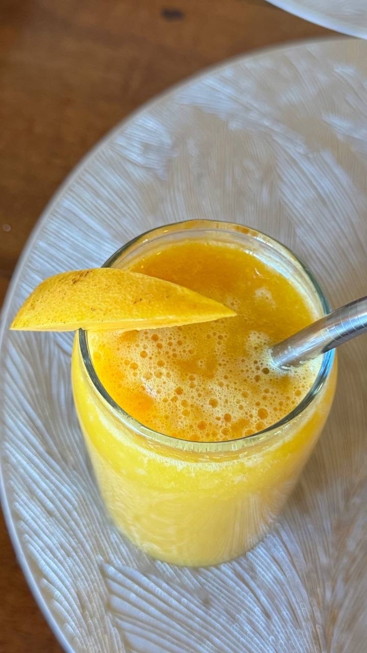 стакан с соком желтого солнечного света с кусочком манго